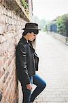 Young woman leaning against brick wall