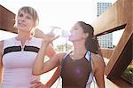 Two women taking a water break from training on urban footbridge