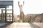 Man training, jumping mid air on footbridge