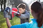 Young man and woman doing boxing training in park