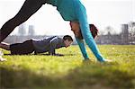 Young man and woman doing push up training on playing field