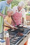 Boy cooking kebabs and burgers on barbecue with father and grandfather