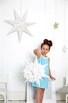 Girl with paper cut-out star against white wall with stars