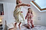 Girls jumping on bed in loft room