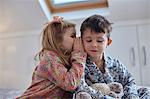 Girl whispering into boy's ear in loft room