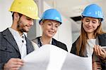 Architect looking at blue print with businesswomen in new office building