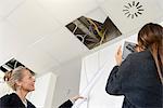 Businesswomen photographing ceiling using digital tablet in new office