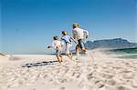 Rear view of father and sons running on beach