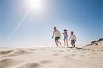 Father and sons running on beach