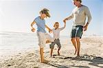 Father and sons on beach holding hands