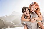 Man in front of rocks giving woman piggyback smiling