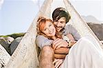 Couple sitting in lace teepee looking at camera smiling