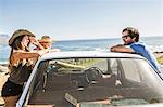 Three mid adult friends leaning on car roof at coast, Cape Town, South Africa