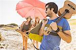 Mid adult women carrying  beach umbrella at beach, Cape Town, South Africa