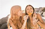 Mid adult female friends eating ice lolly on beach, Cape Town, South Africa