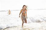 Two women wearing bikini's running in sea, Cape Town, South Africa