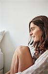 Portrait of young woman sitting on floor next to bed