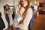 Portrait of young woman and sleeping baby daughter at family gathering