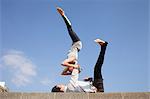 Man and woman practicing acrobatic yoga against blue sky