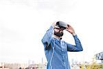 Young male designer testing virtual reality headset on office roof terrace