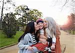 Mother and grandmother kissing smiling girls cheeks