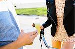 Cropped shot of young couple holding juice and coffee drinks at coast