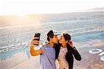 Young couple puckering up for smartphone selfie on beach, Venice Beach, California, USA