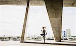 Young woman exercising under bridge