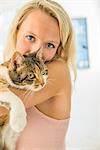 Woman nuzzling cat, looking at camera