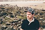 Man wearing baseball cap looking out from beach, Crystal Cove State Park, Laguna Beach, California, USA