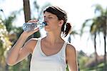 Woman drinking bottled water outdoors