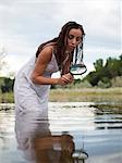 USA, Utah, Provo, woman wading in lake with magnifying glass