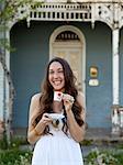 USA, Utah, Provo, Young woman standing in front of house, holding cup