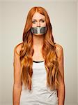 Studio shot of young woman gagged with silver tape