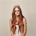 Studio portrait of redhead woman with tiara and broken sign on forehead