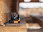 Close-up of toy figure driving toy forklift on wooden shipping pallets