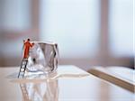 Miniature figure of window cleaner washing an ice cube on top of a fridge