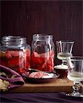 Dish and jars of homemade poached quince on cutting board