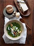 Overhead view of italian wedding soup with bread roll and parmesan cheese