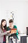 Colleagues in office using digital tablet smiling