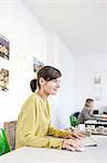 Side view of mature woman in office using computer smiling