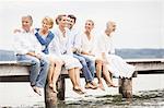 Group of friends, sitting in row on edge of pier