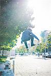 Young male skateboarder doing skateboarding jump on sidewalk