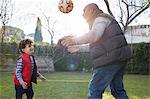 Grandfather and grandson playing with football smiling