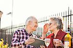 Senior couple on city rooftop garden using digital tablet