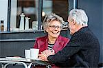 Romantic senior couple holding hands at sidewalk cafe