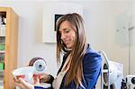 Optician holding anatomical model of eyeball smiling