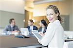 Portrait smiling businesswoman using digital tablet in conference room meeting