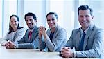 Portrait of smiling business people sitting in a row in conference room