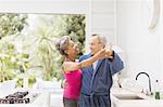 Playful mature couple dancing in kitchen